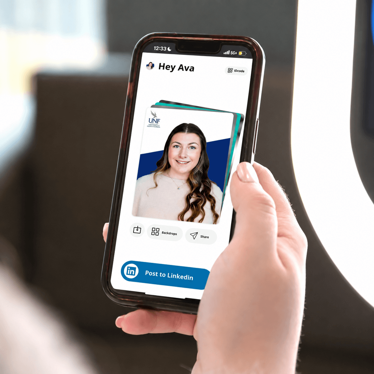 A phone showing a branded Popcam headshot ready to share